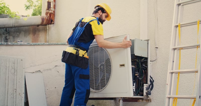 worker performing maintenance tasks to an air conditioner at a facility