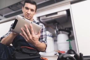 worker looking at a cmms on a tablet to update his maintenance team