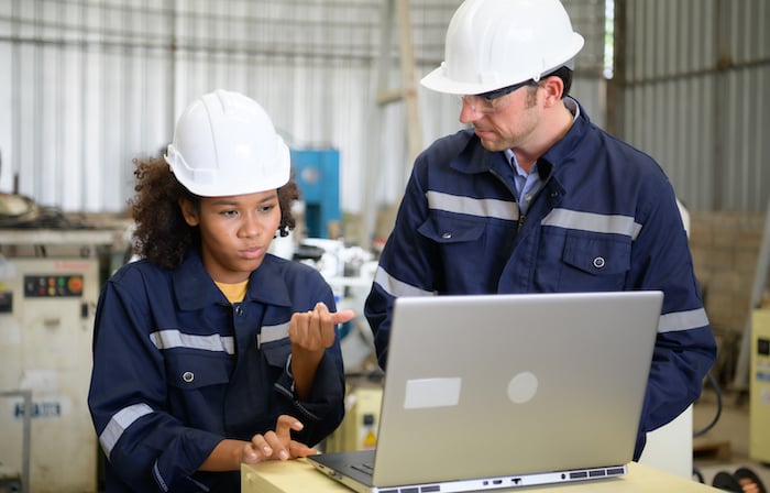 A technician and a maintenance team discussing failure metrics in front of an image showing the mean time to failure graph for inventory management system