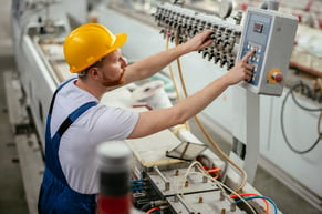 worker helping to reduce unplanned maintenance by performing routine work on a machine